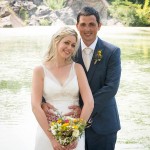 Groom stands behind bride with colorful wedding flowers