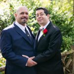 Two grooms pose for portrait in Shakespeare Garden