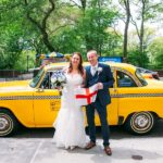Bride and Groom posing with British flag in front of Vintage NYC Taxi