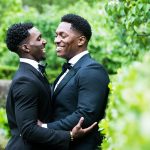 Two grooms hugging by trees in Central Park