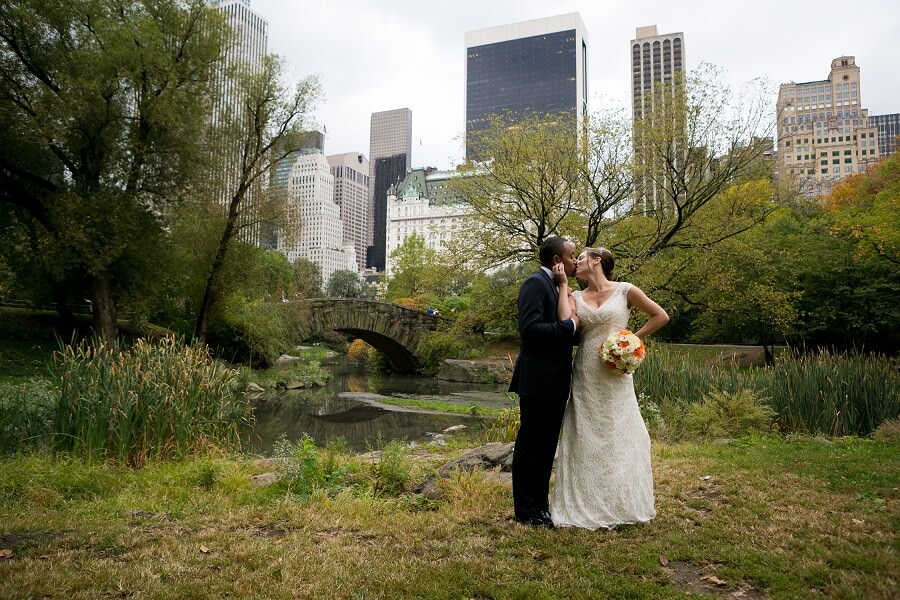 Bride and groom pose behind Gapstow Bridge in Central Park