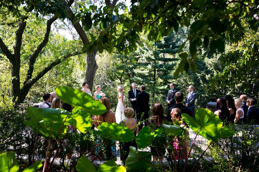 Wedding ceremony at Shakespeare Garden seen through trees
