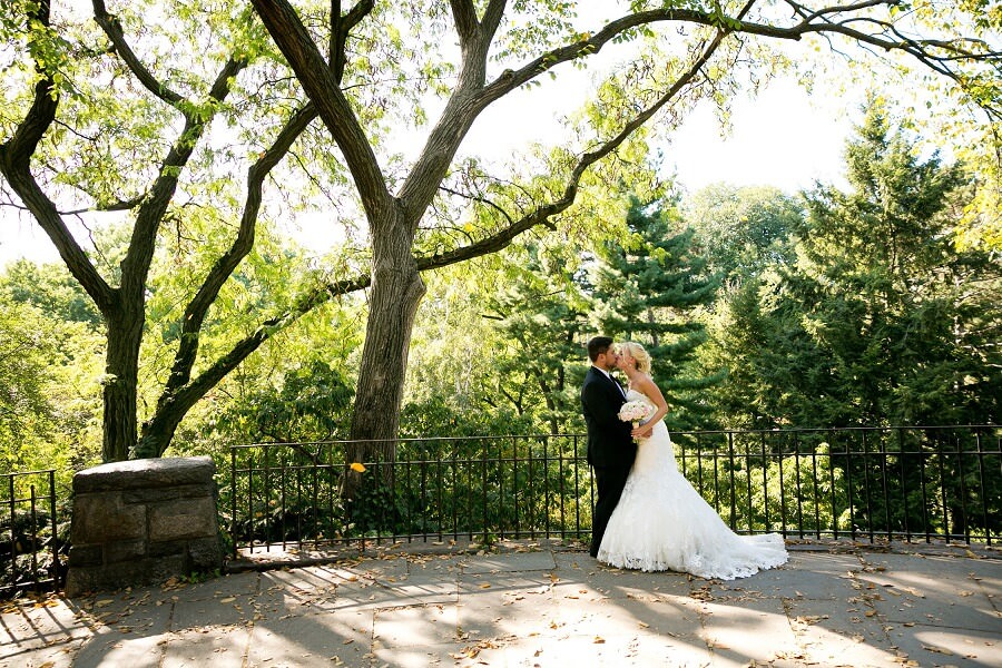 Newlyweds kiss in front of large tree at Shakespeare Garden