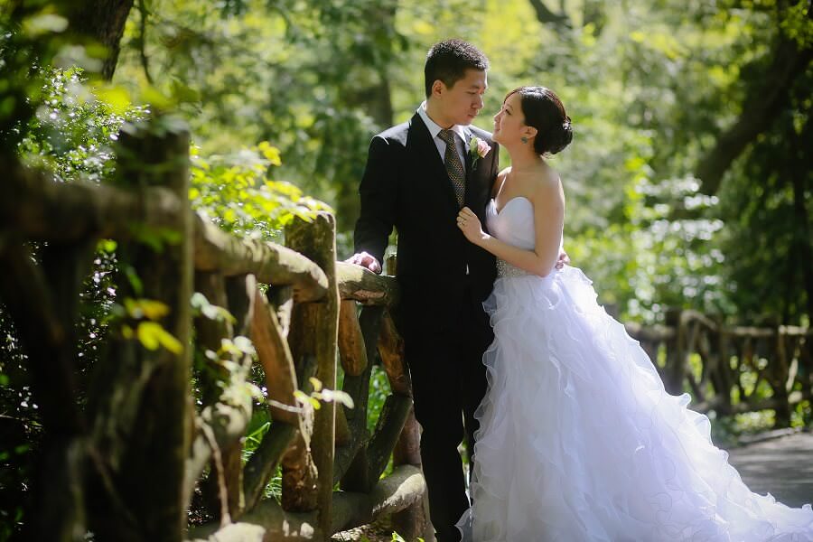 Bride and groom against wooden railing in Shakespeare Garden