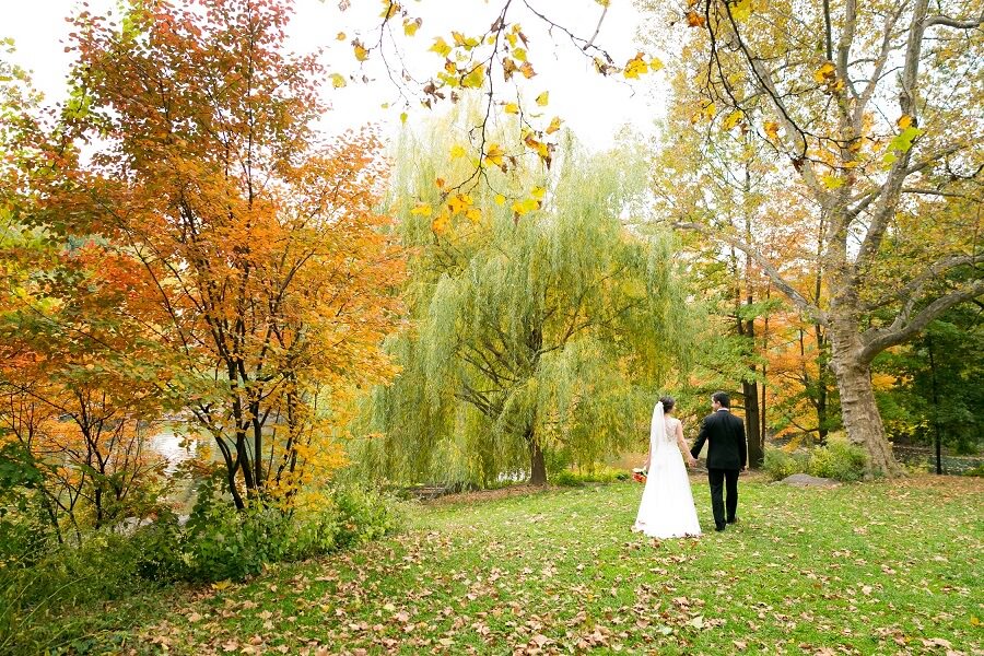 Wedding couple walking through fall foliage along The Pool in Central Park