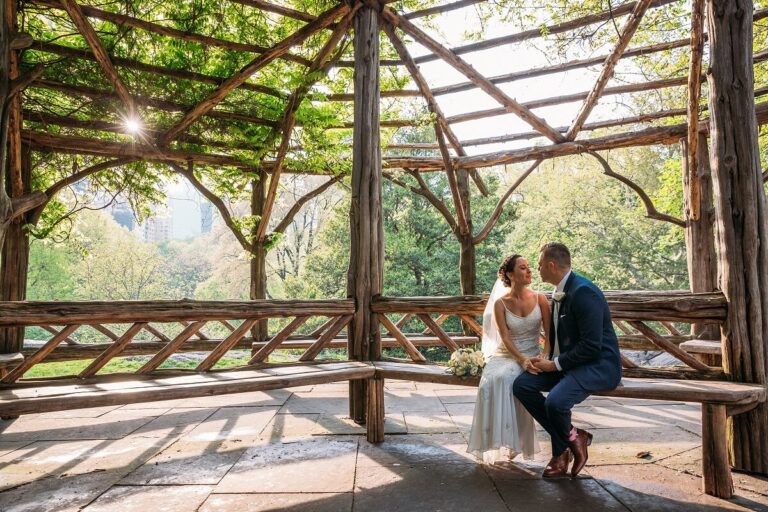 NYC Outdoor Wedding Venues & Locations: Newlyweds pose on Cop Cot bench in Central Park