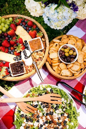 Salad and fruit displayed on platters at picnic