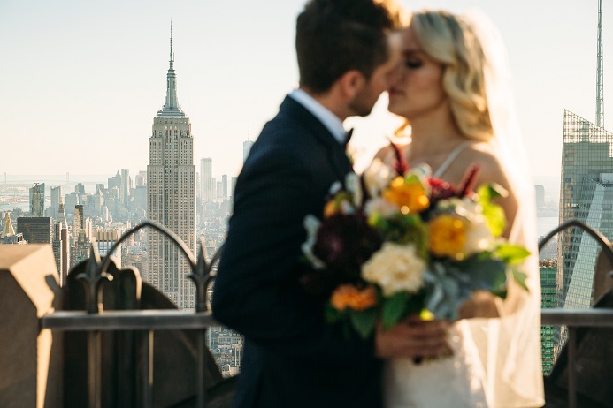Newlyweds kissing with Empire State building in background