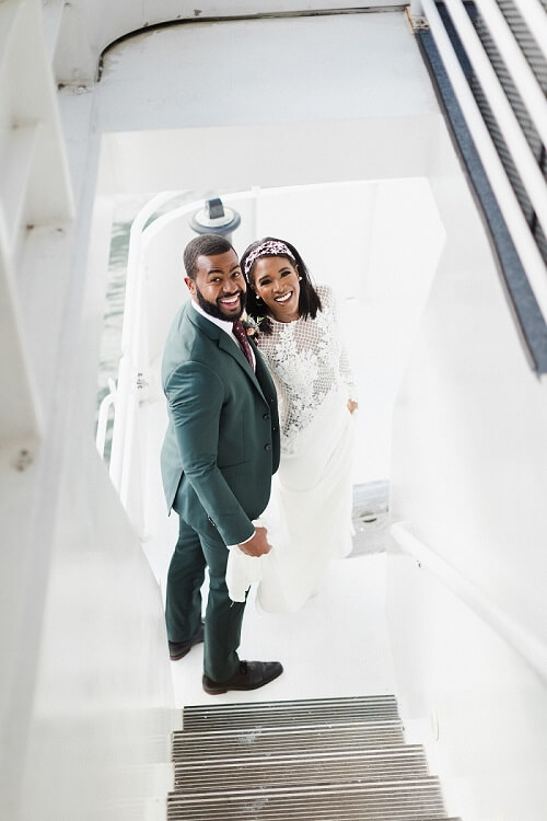 bride and groom smiling up at photographer on nyc cruise
