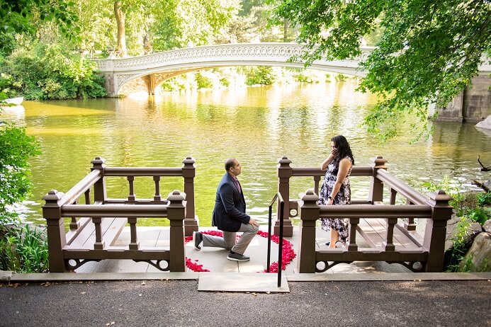 Surprise proposal at Bow Bridge landing in Central Park with rose petal heart